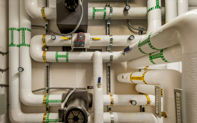 Teknisk installation med VVS-rør, ventiler og måleinstrumenter. Billedet illustrerer et VVS- og ventilationsanlæg i forbindelse med en stilling som projektassistent/serviceleder i Grønland.